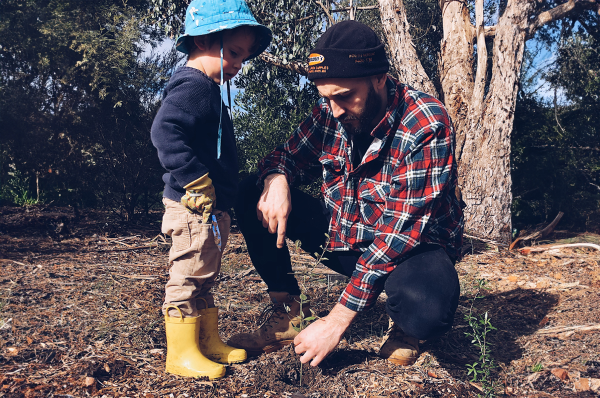 Jardinero con niño pequeño plantando plantas